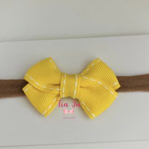 Faixa com laço cruzado amarelo pespontado